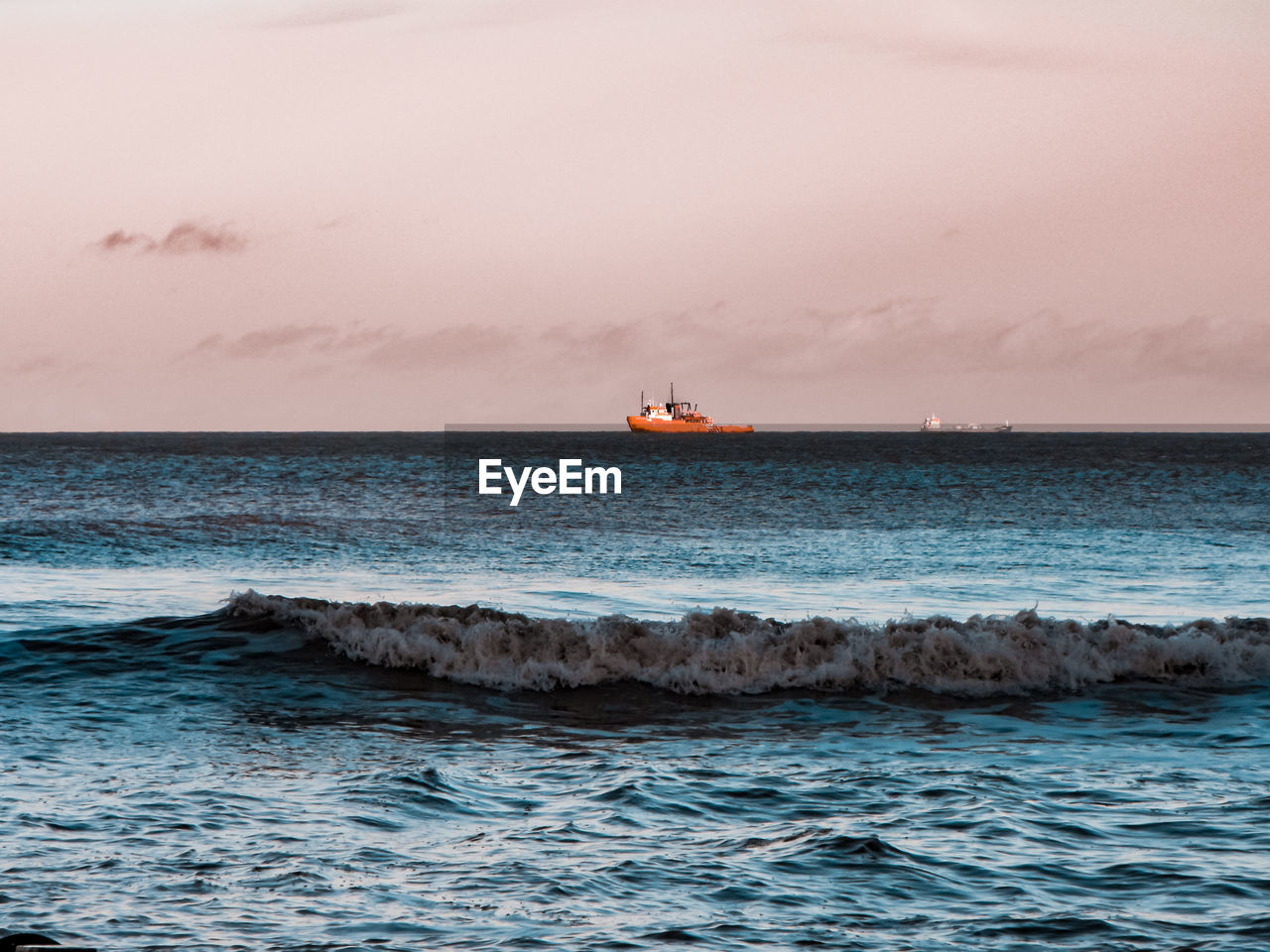 Scenic view of sea and boat against sky during sunset