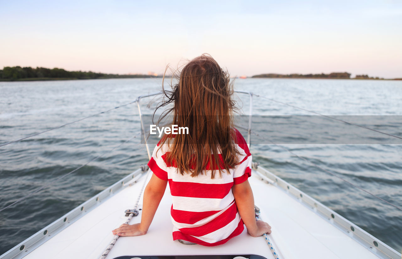 Rear view of girl sitting on boat in sea