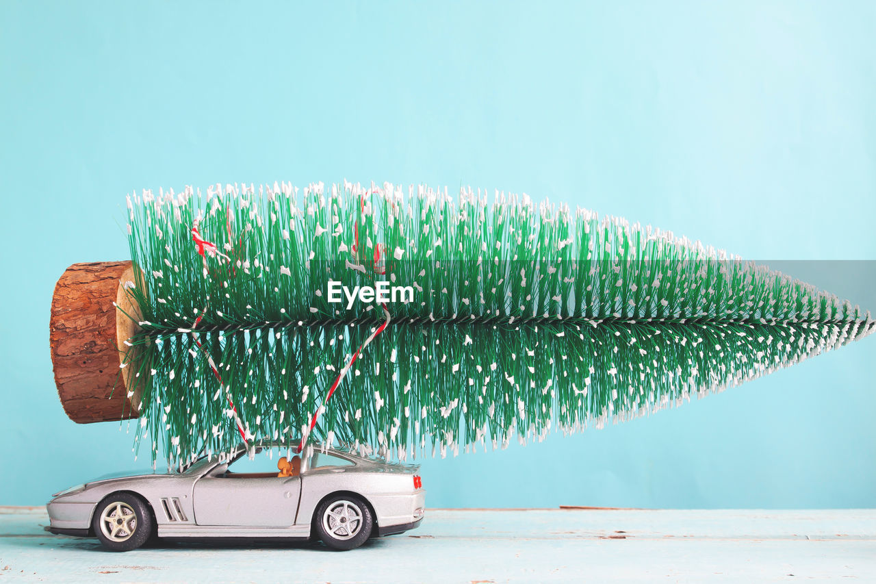 Christmas tree on toy car against blue background