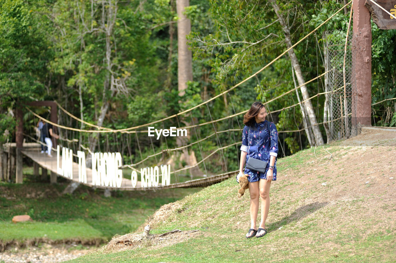 Woman standing on field against trees