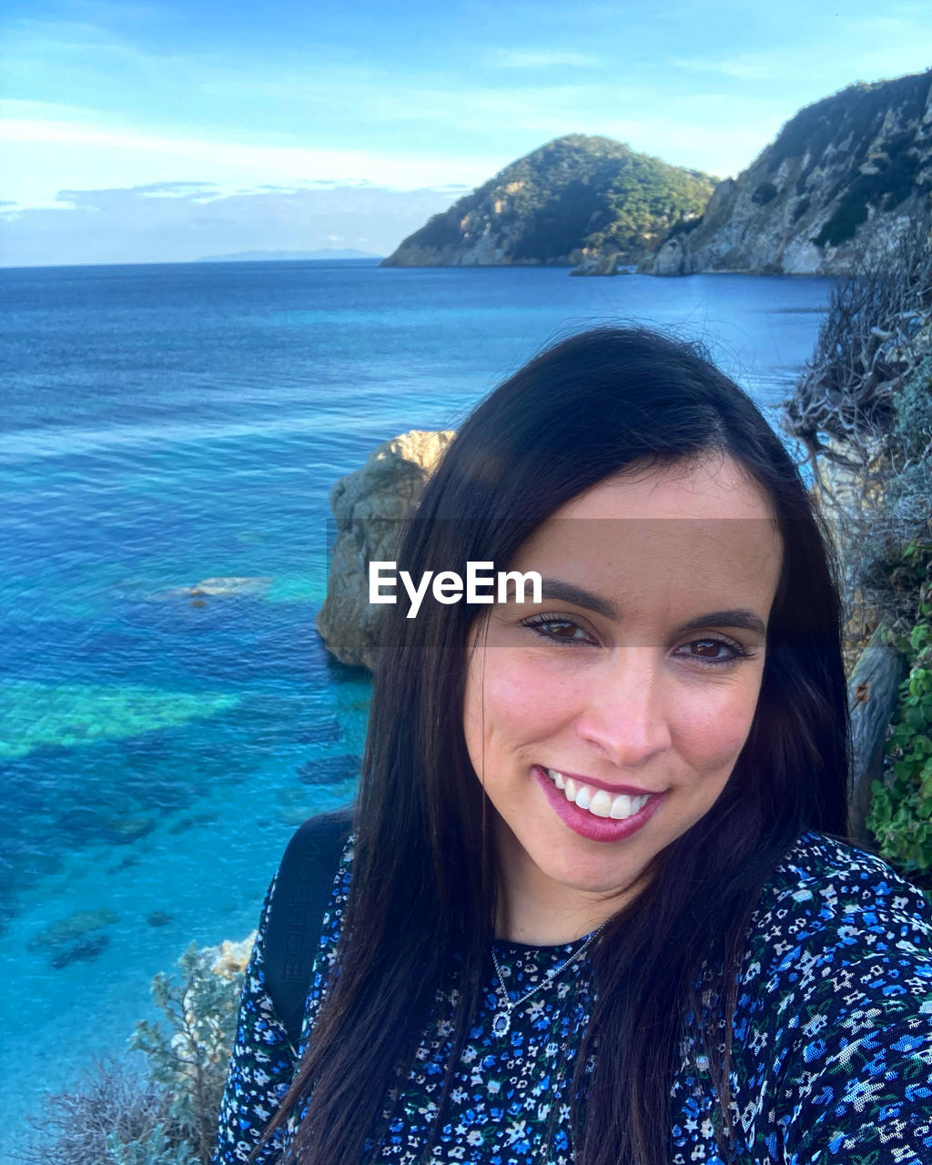 portrait of smiling young woman against sea