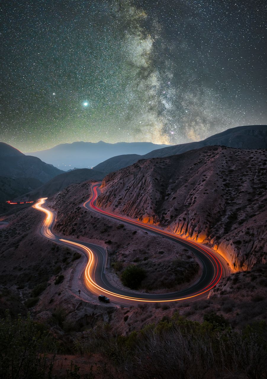 The colorful roads around the mountains reflect the stars