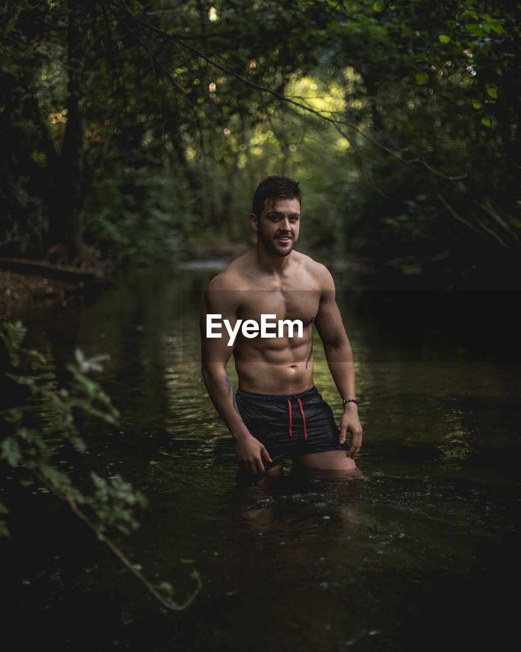 Full length of shirtless man in forest
