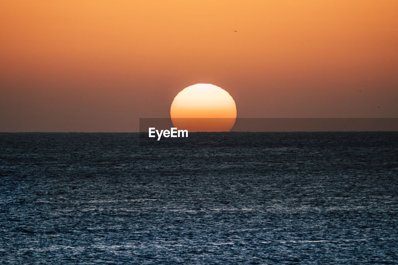 SCENIC VIEW OF SEA AGAINST SKY AT SUNSET