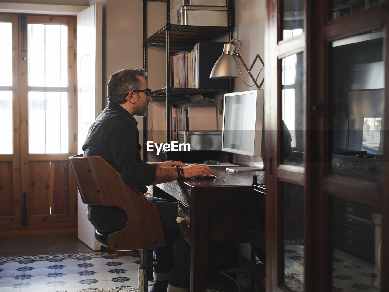 Man working at home desk with computer via internet