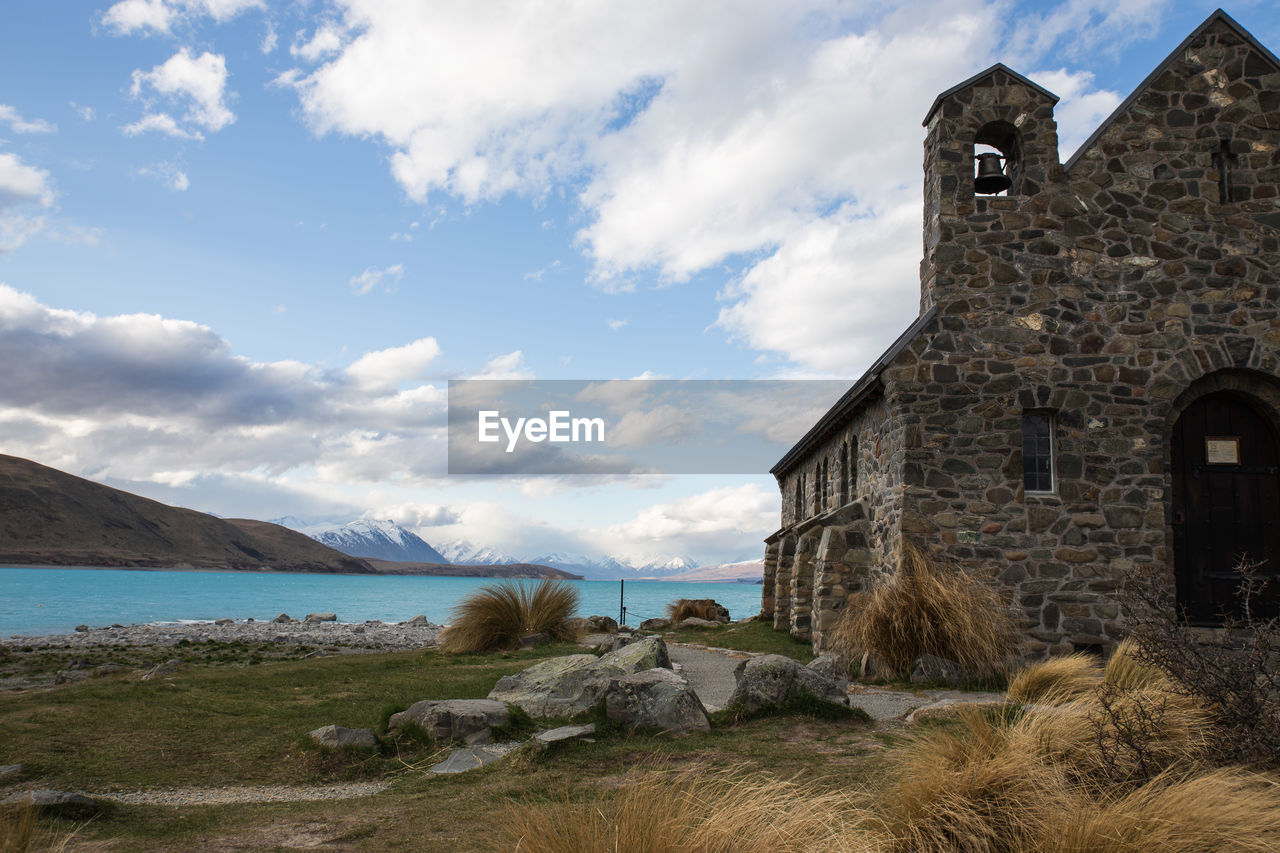 Building by lake against cloudy sky