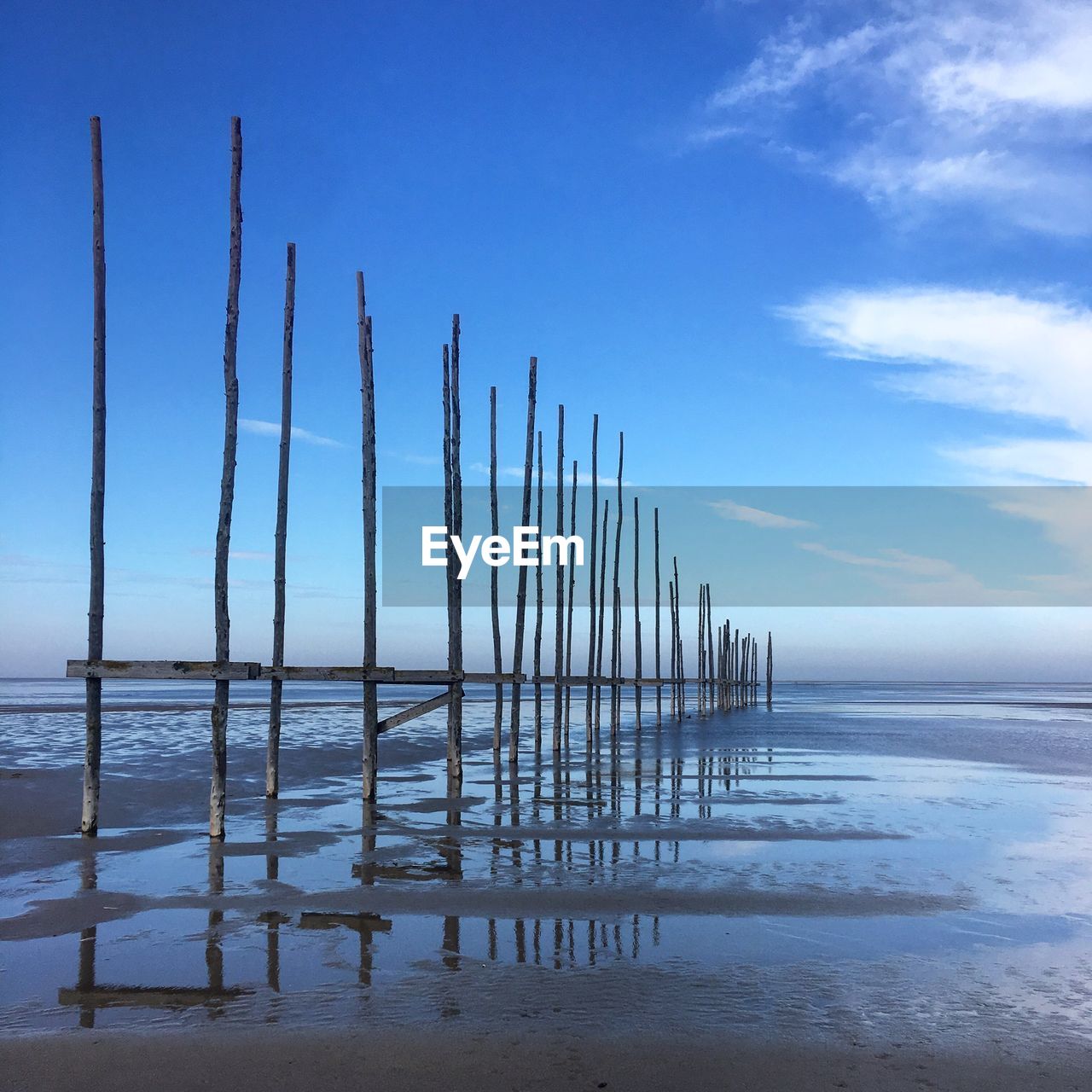 WOODEN POSTS IN SEA AGAINST SKY
