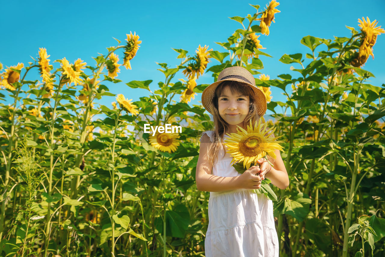 Portrait of girl wearing cap standing amidst plants