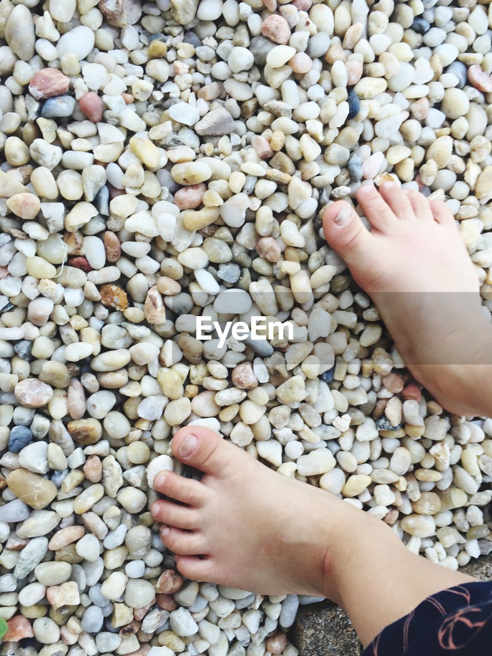 Close-up low section of boy standing on pebbles