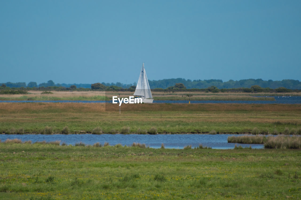 BOAT SAILING ON LAKE AGAINST SKY