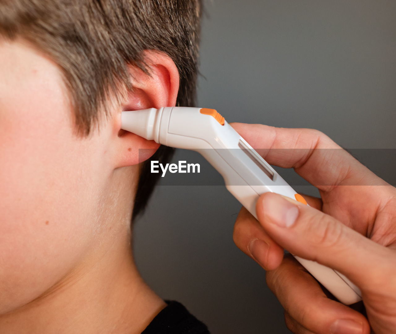 Close up of child getting temperature taken with an ear thermometer.