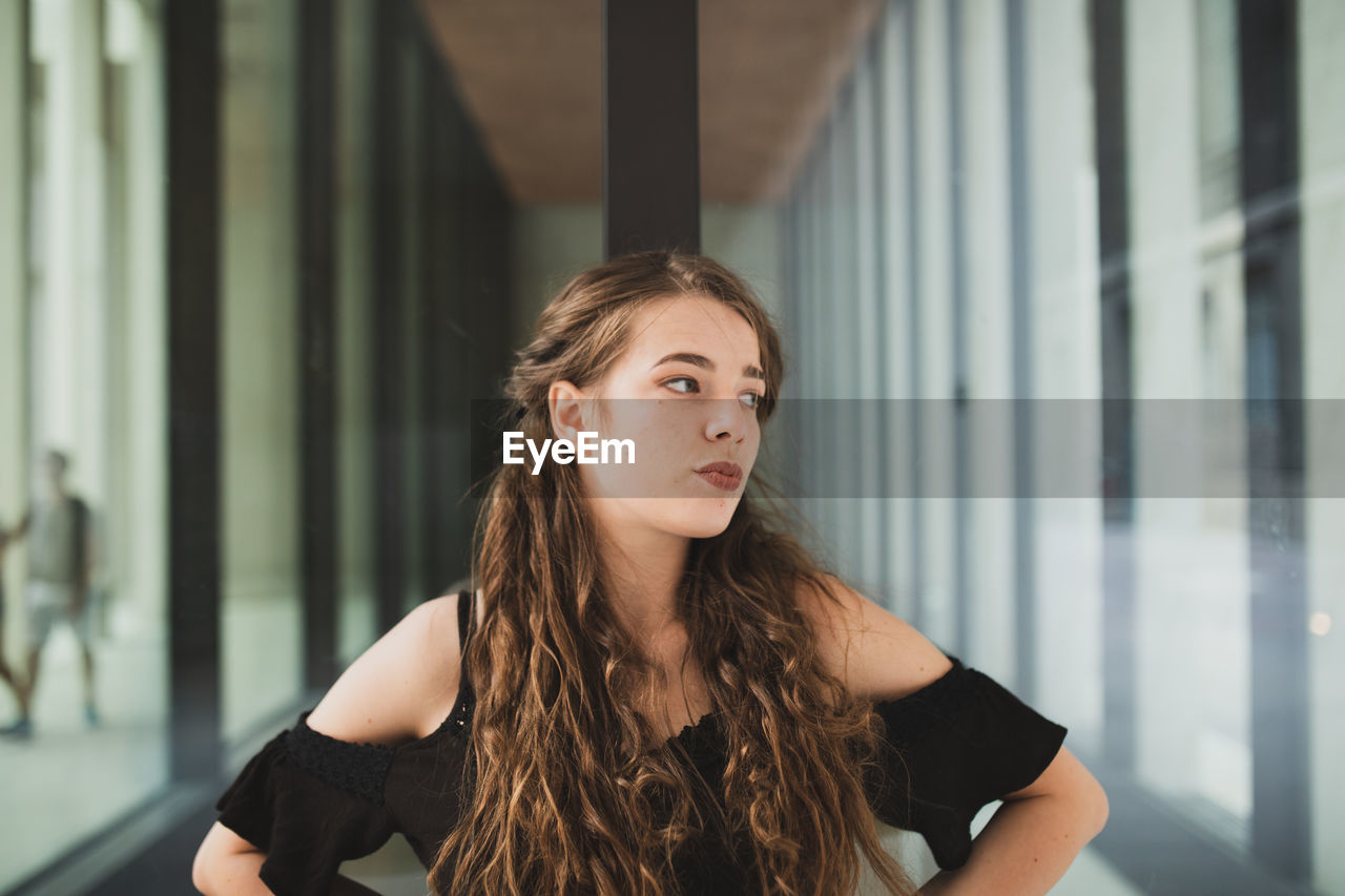 Young woman looking away while standing in building