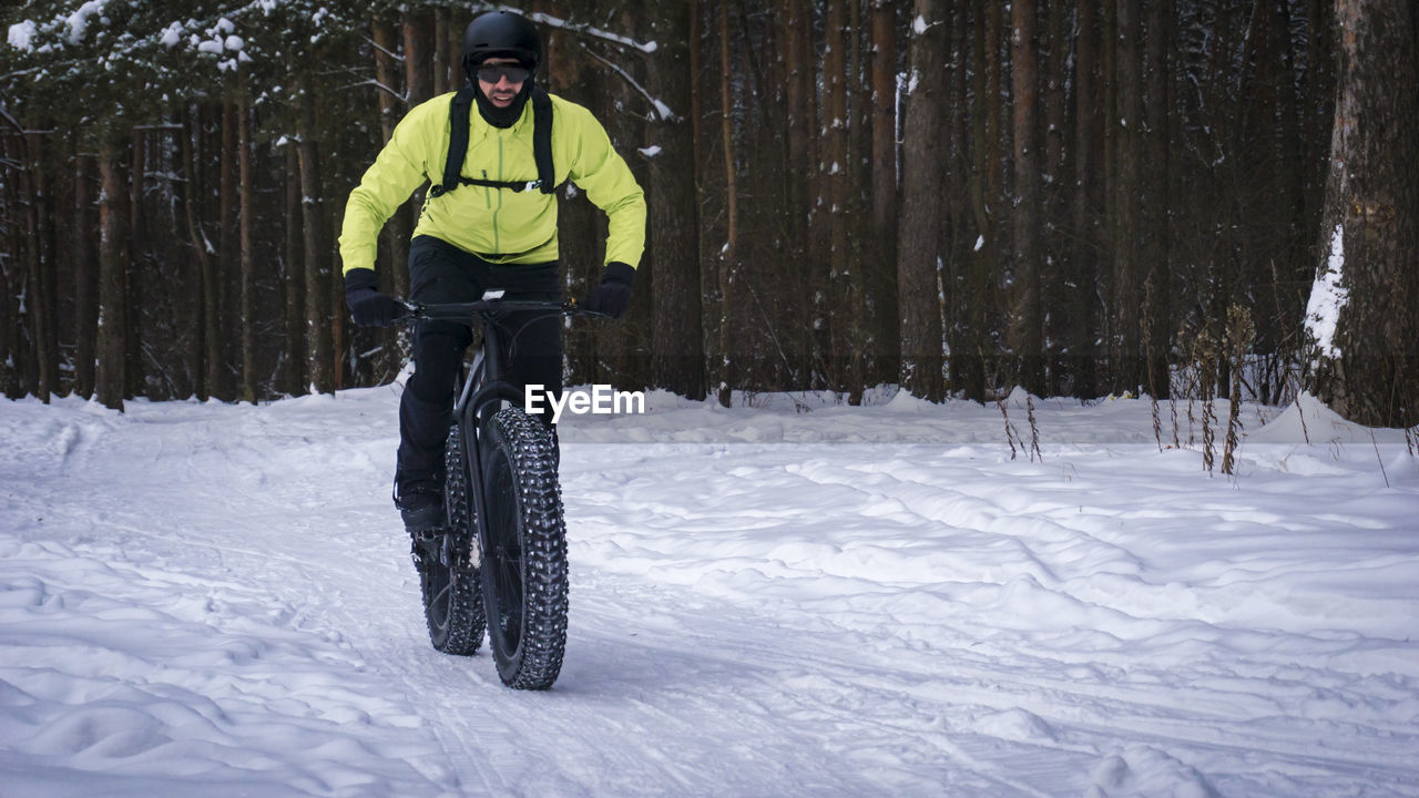 Man riding bicycle on snow covered field