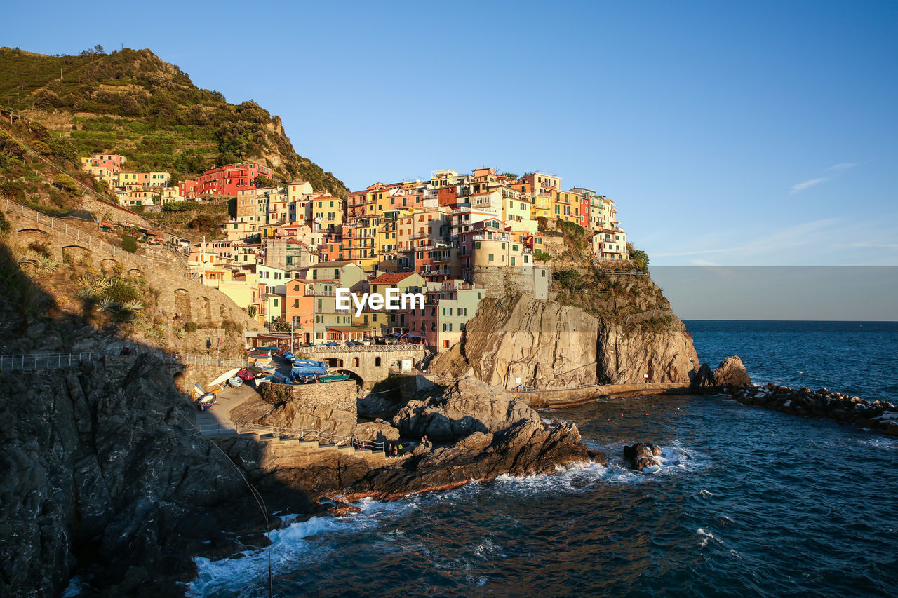 Buildings at sea shore at manarola against clear blue sky