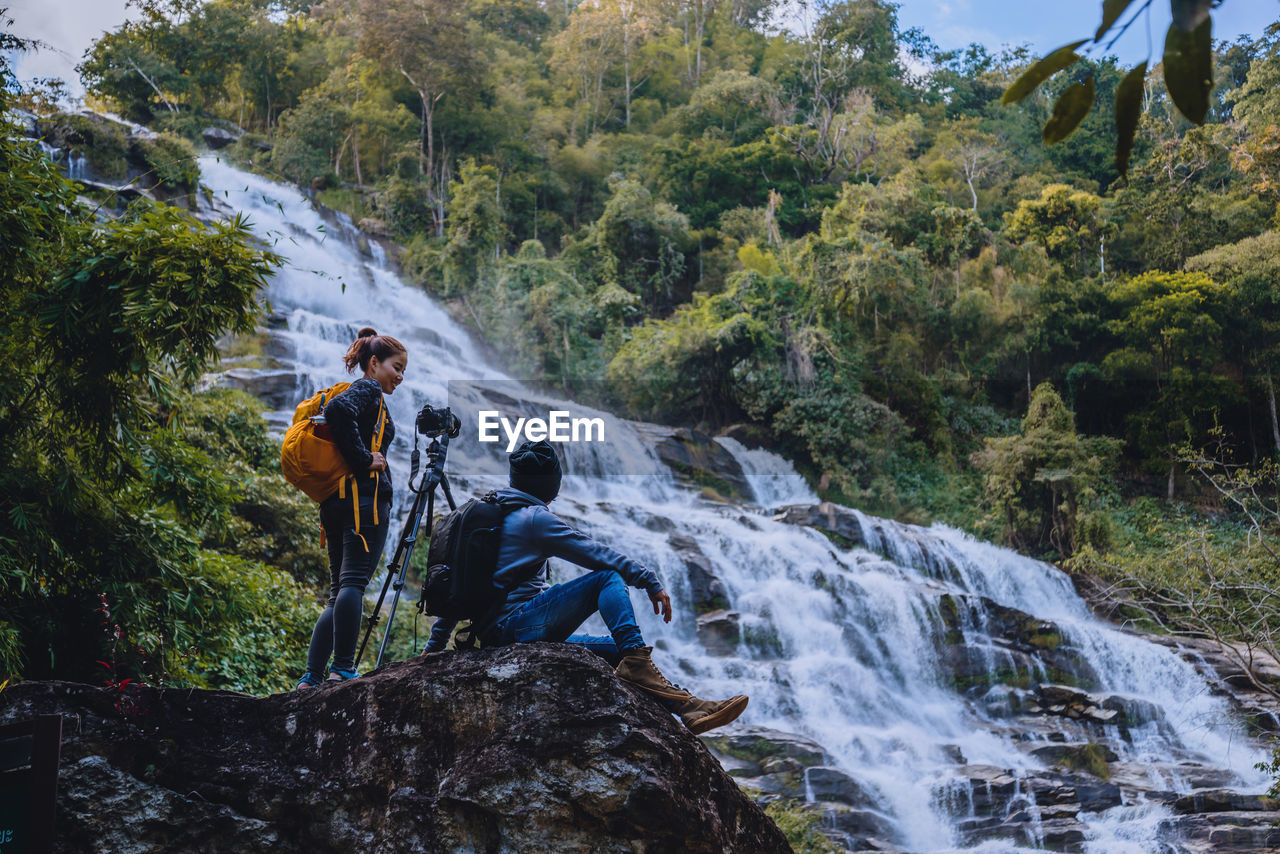 Friends photographing waterfall in forest