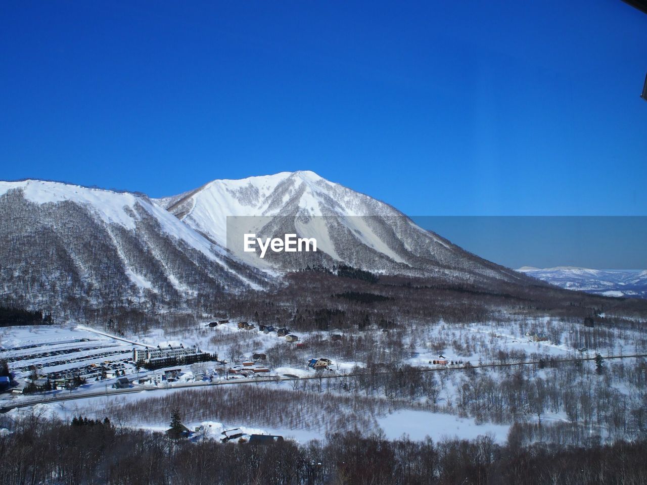Scenic view of snow covered mountains against blue sky