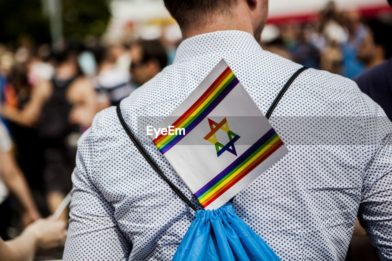 Midsection of man with multi colored israeli flag on back during gay pride parade