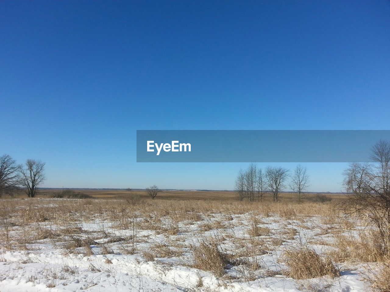 Snow covered landscape against clear blue sky