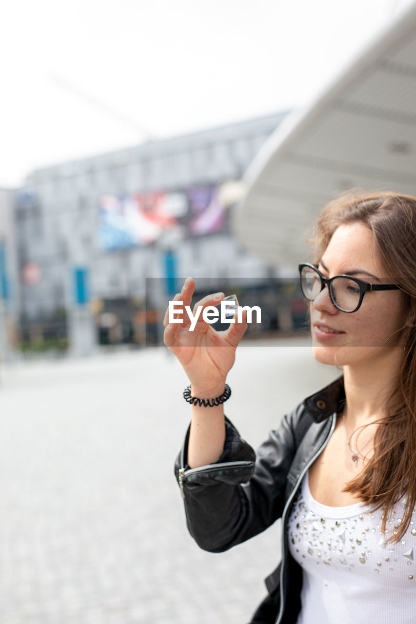 Portrait of young woman holding eyeglasses