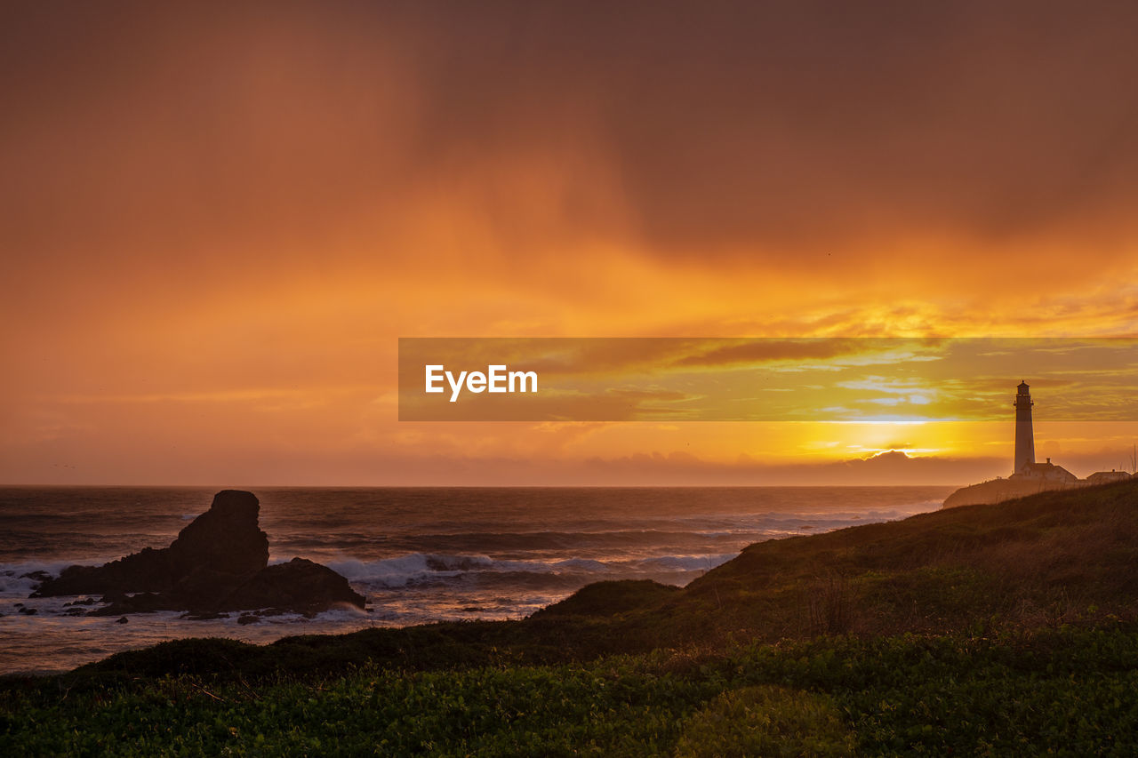 Scenic view of sea against cloudy sky during sunset