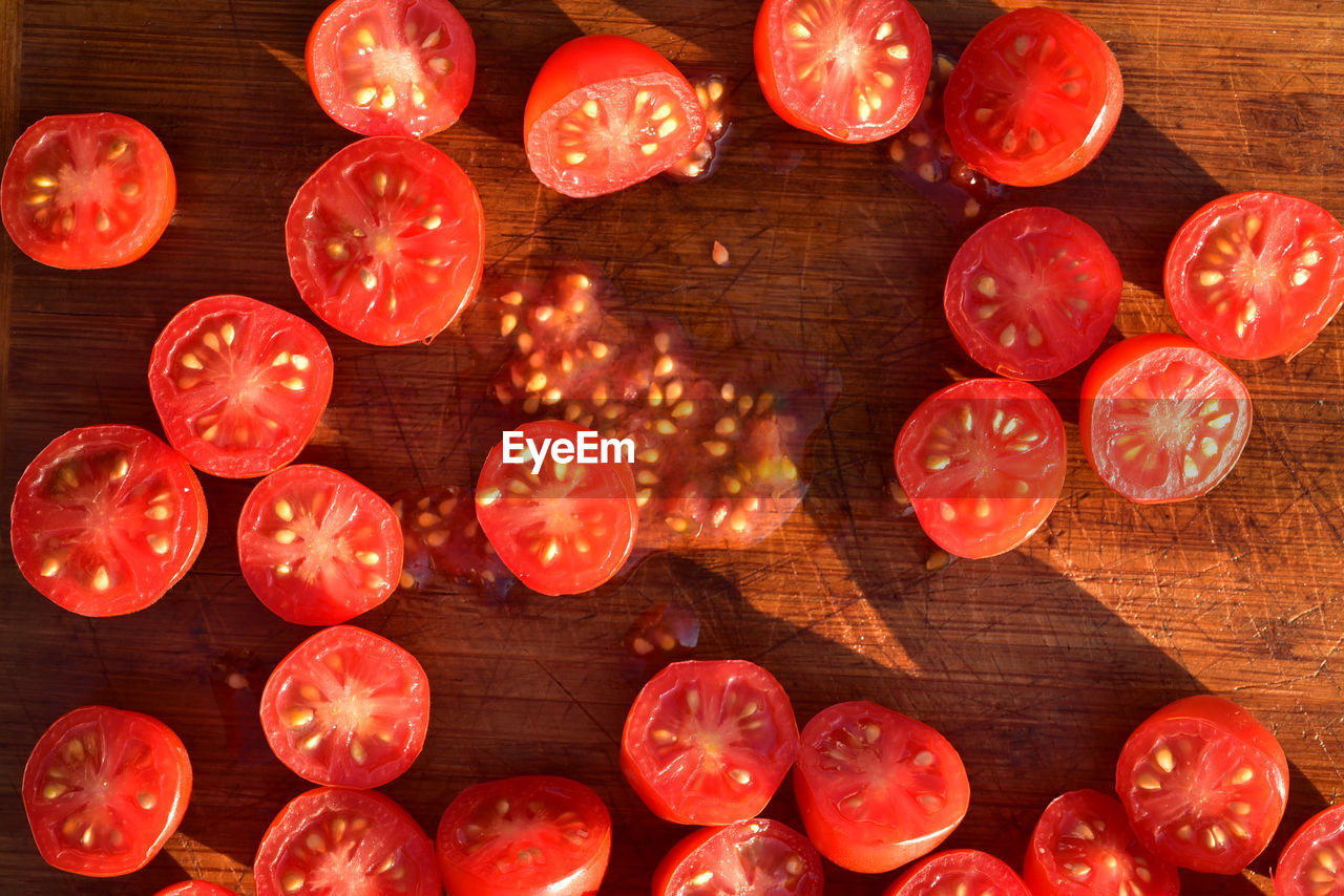 Above view of grape tomatoes cut into halves on wood cutting board