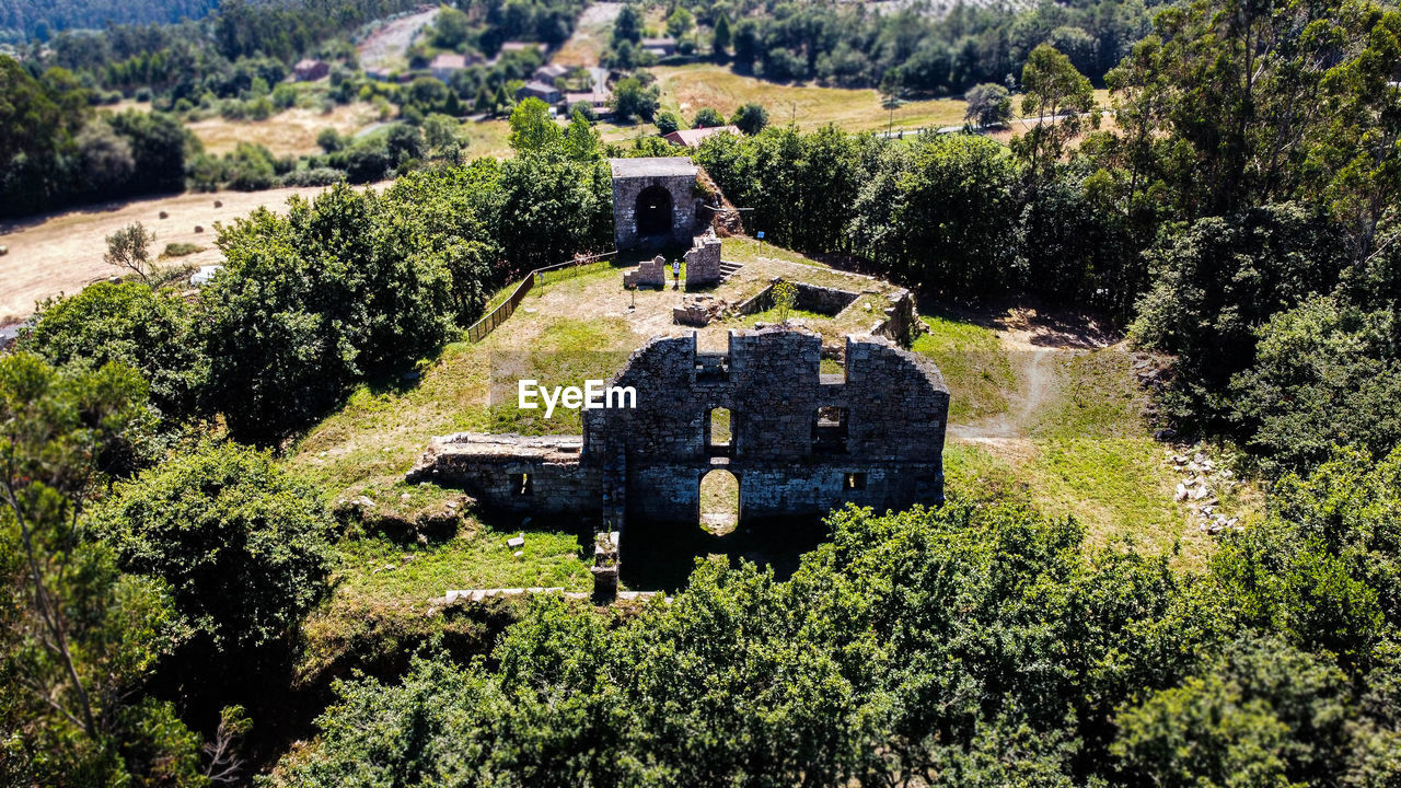 OLD RUIN AMIDST TREES ON FIELD AGAINST BUILDING