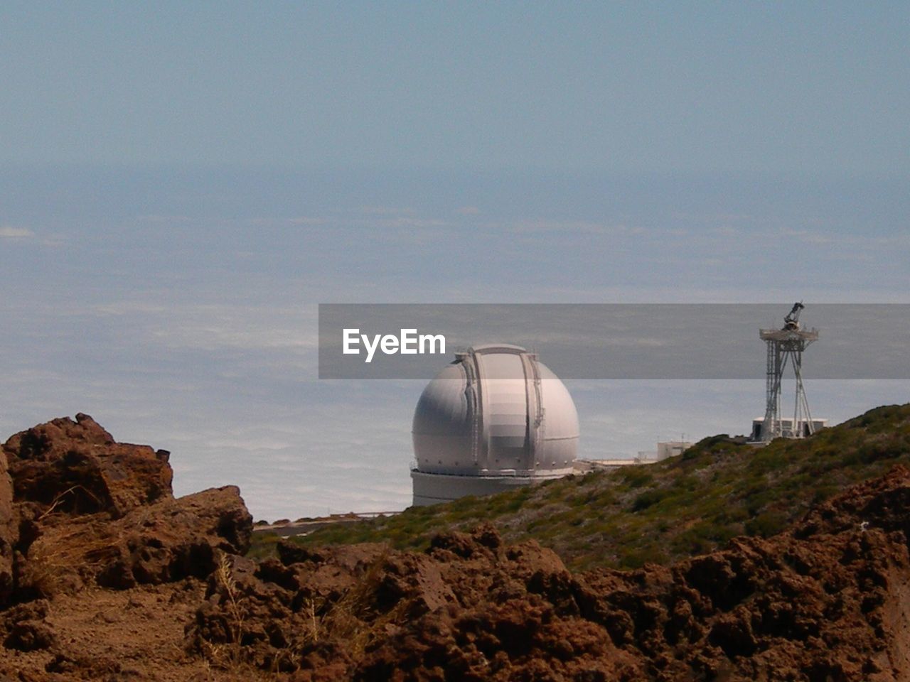 Scenic view of rocks  and astronomy telescope against sky