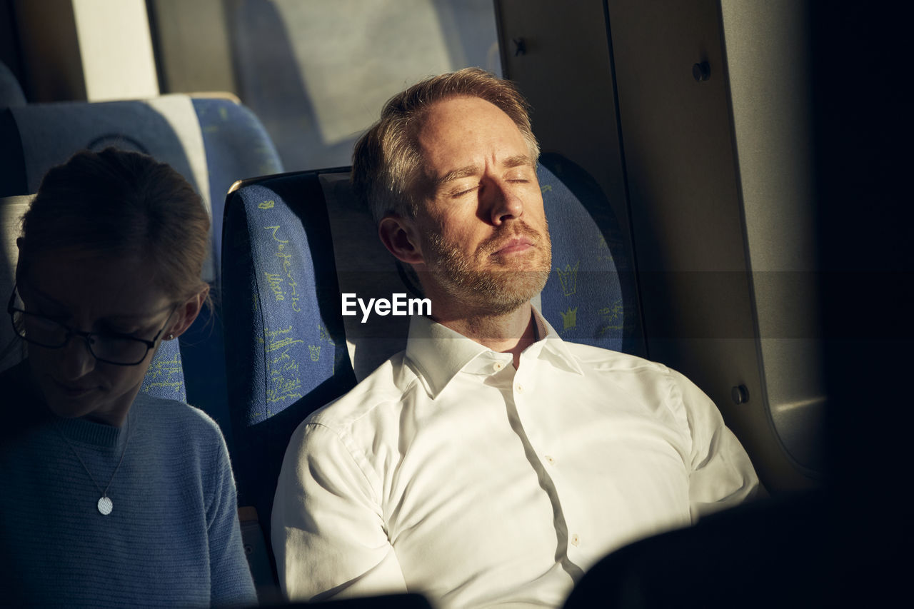 Man sitting in train with eyes closed