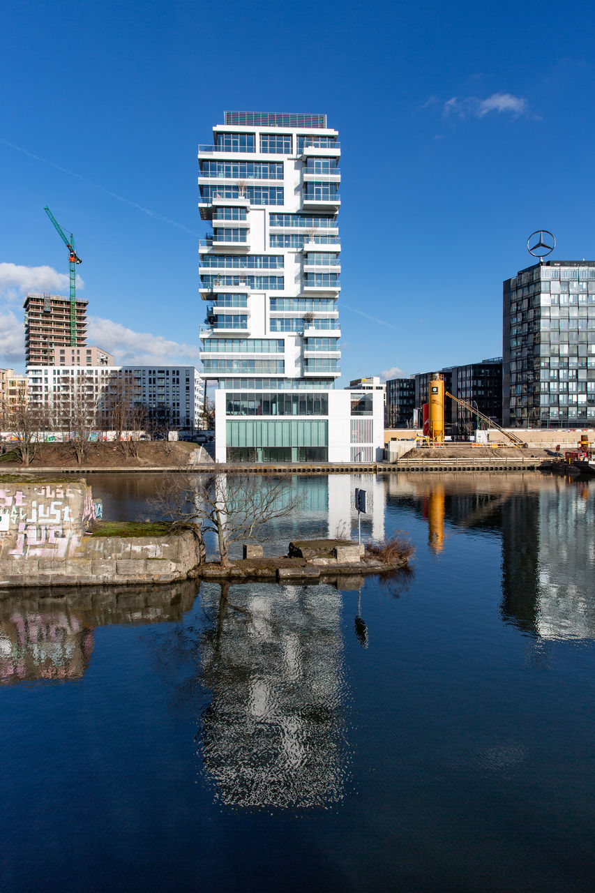 Reflection of buildings in river against blue sky