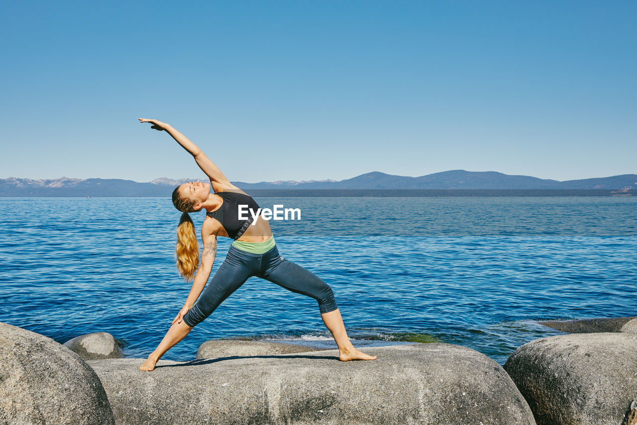 Young woman practicing yoga on lake tahoe in northern california.