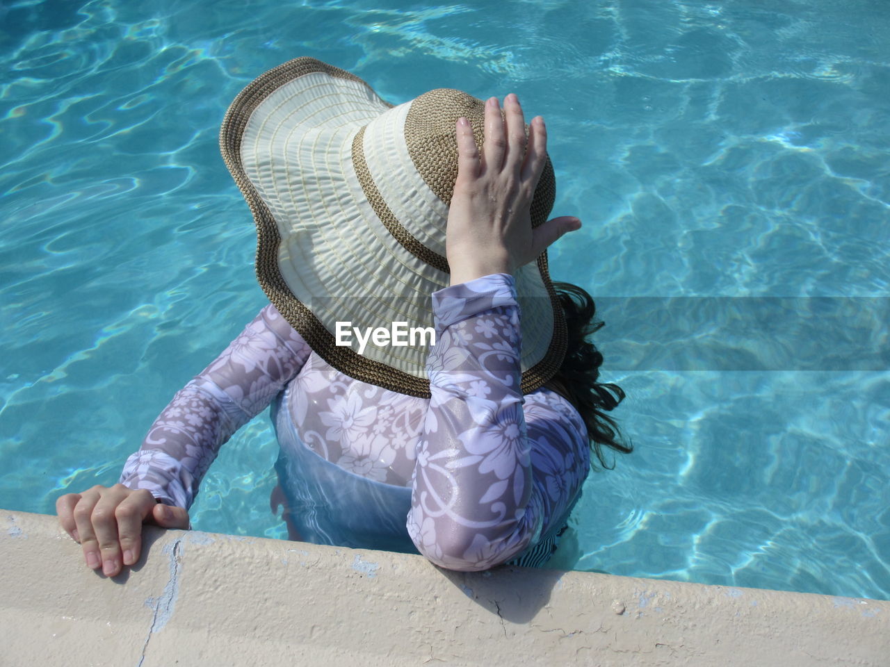 High angle view of woman wearing hat standing in swimming pool