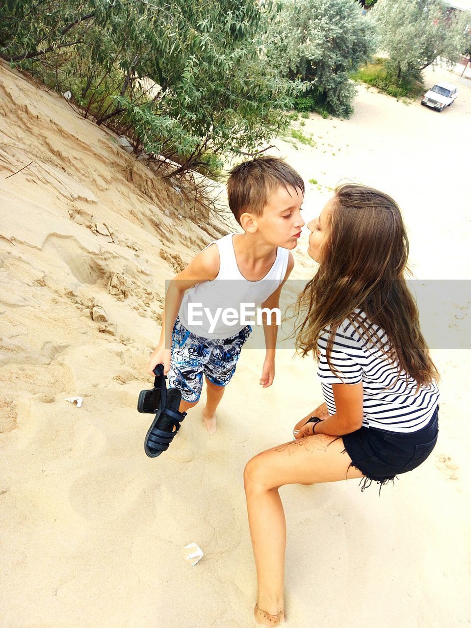 Siblings kissing while standing on sand