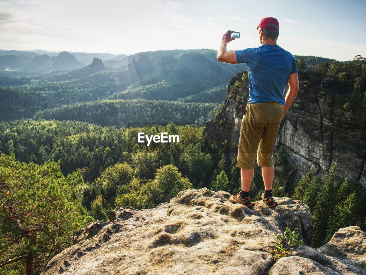 Smart phone mobile photography of spring hilly landscape. focus to man hands with phone