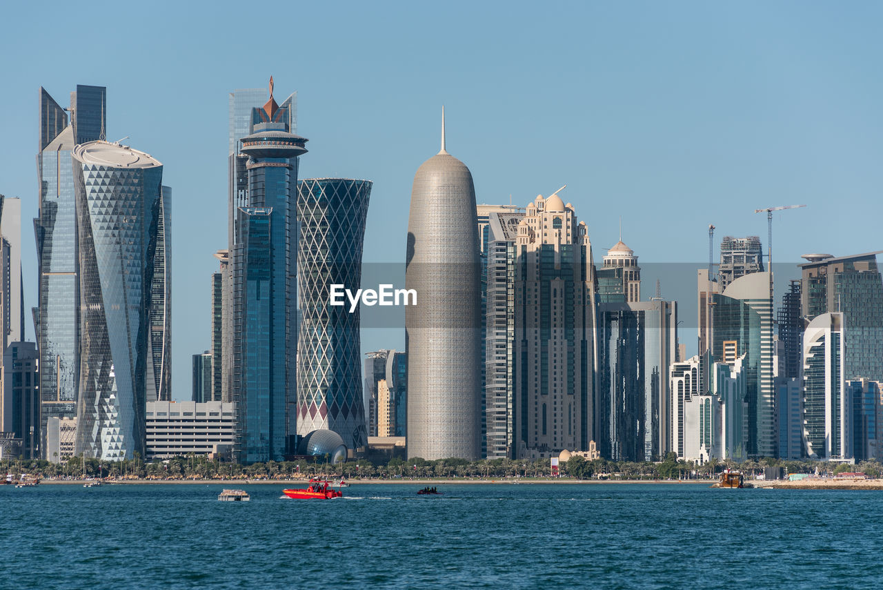 Sea by cityscape against sky