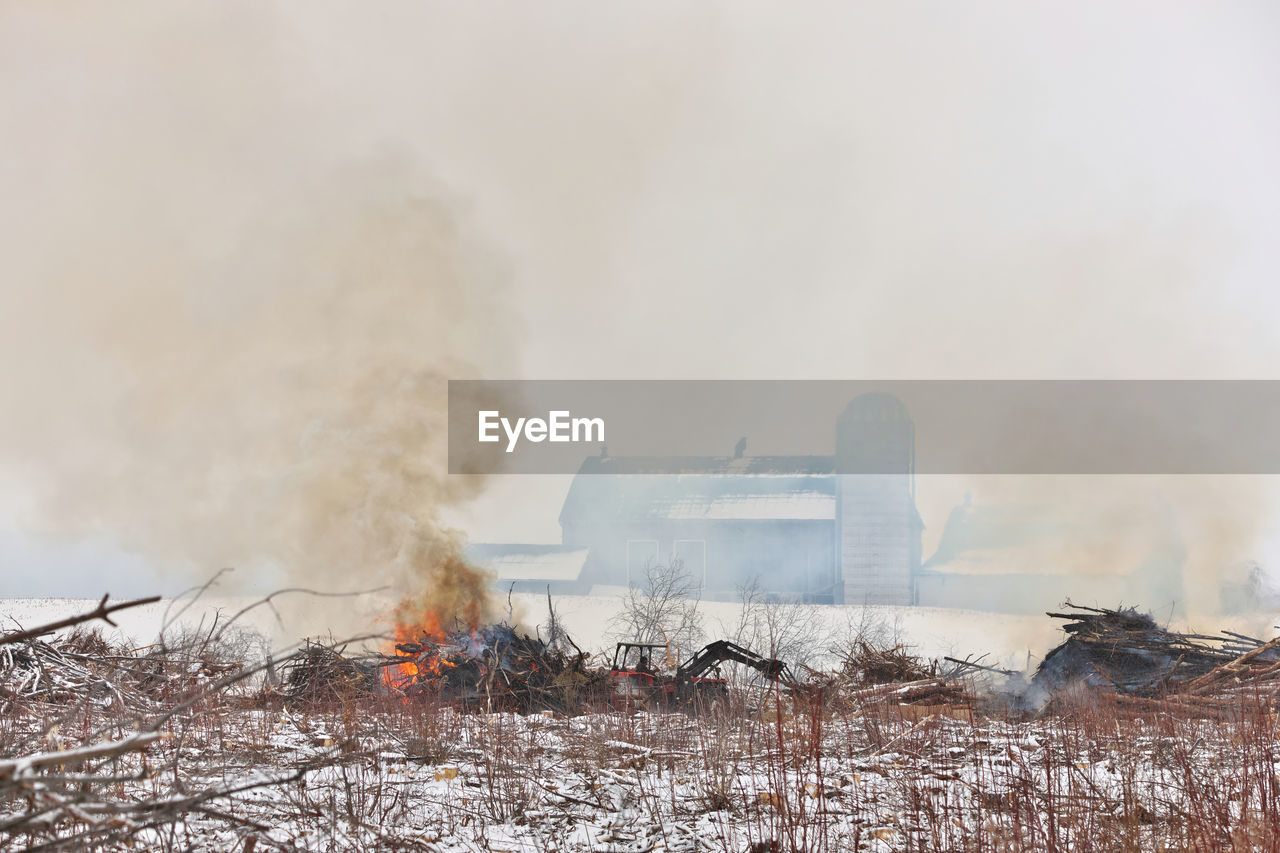 Tractor moves brush during a controlled burn on a farm to make more arable land