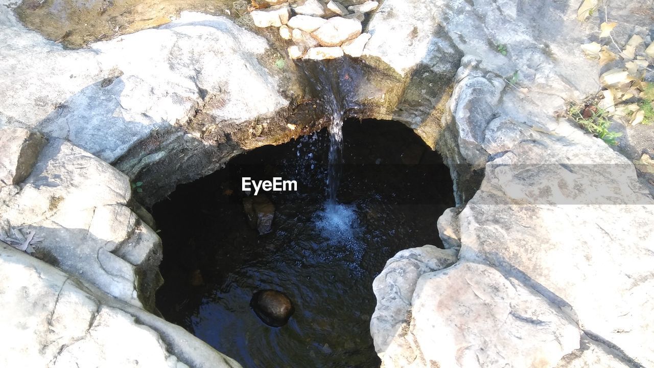 HIGH ANGLE VIEW OF STONES IN WATER