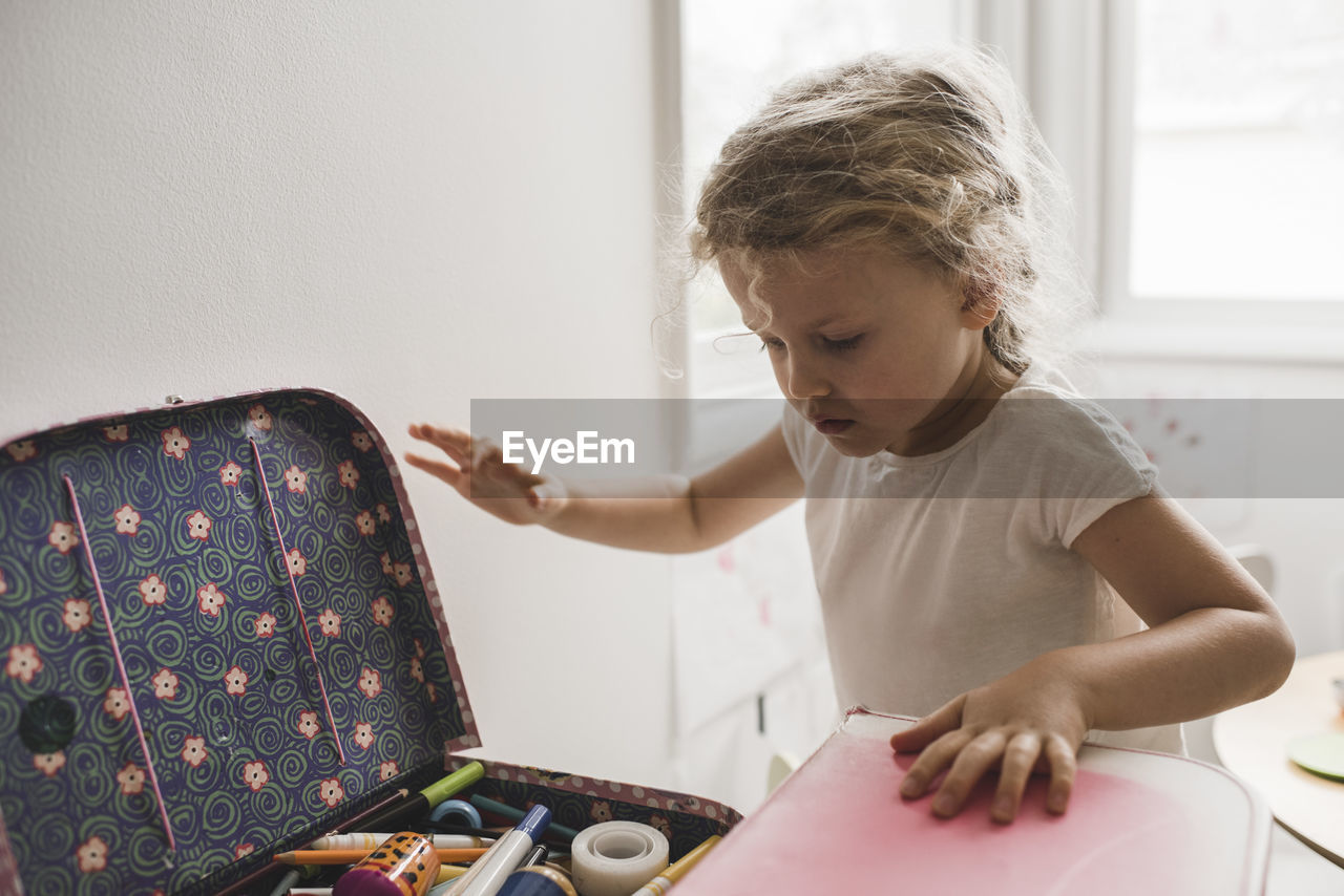 Girl searching for toys in suitcase at playroom