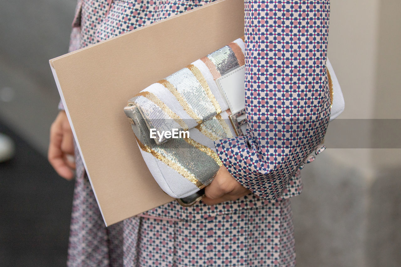 Midsection of woman holding purse and file