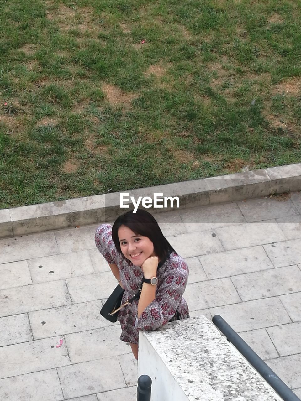 High angle portrait of a smiling young woman on footpath