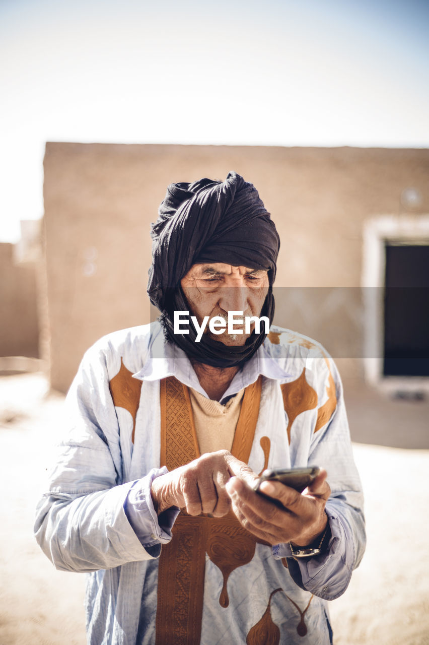 Senior man using cell phone in smara refugee camp, tindouf, algeria