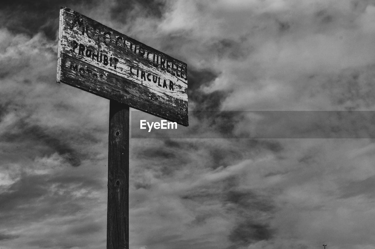 Close-up of road sign against cloudy sky