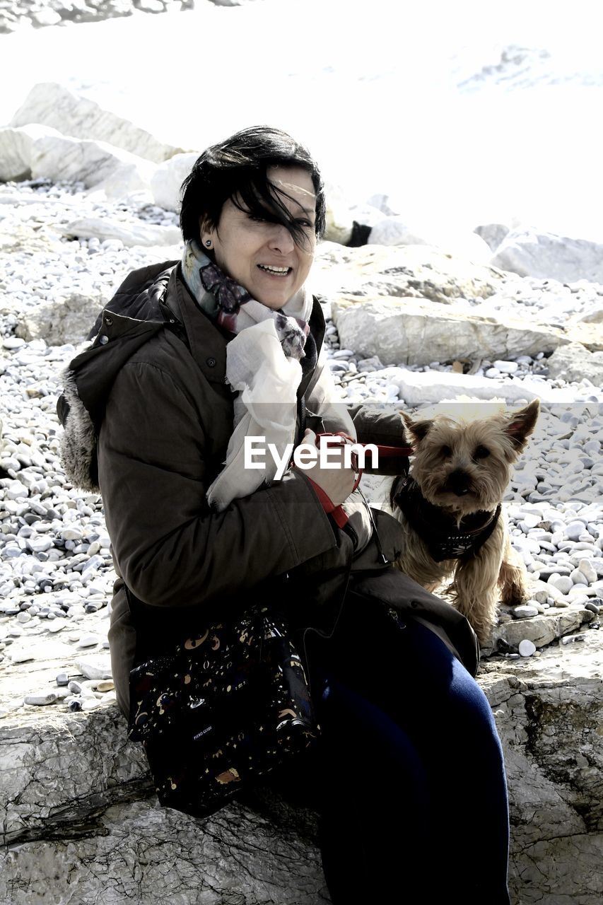 Portrait of woman with dog sitting on rock