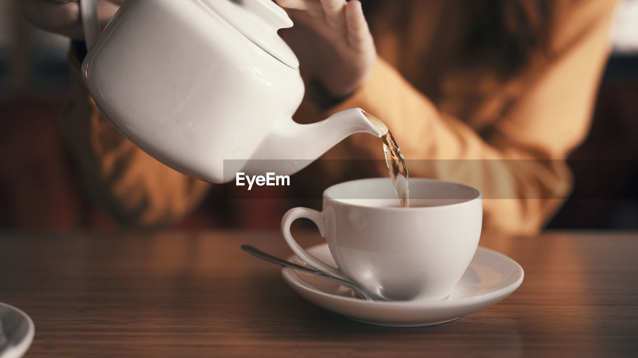 Midsection of woman pouting tea in cup