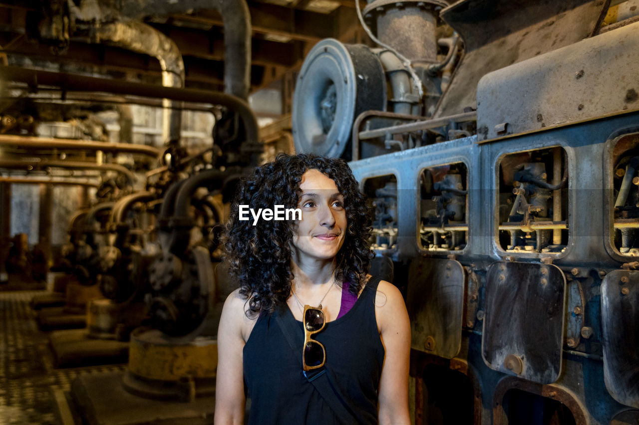 Portrait of a mixed race woman smiling while posing inside an abandoned factory.