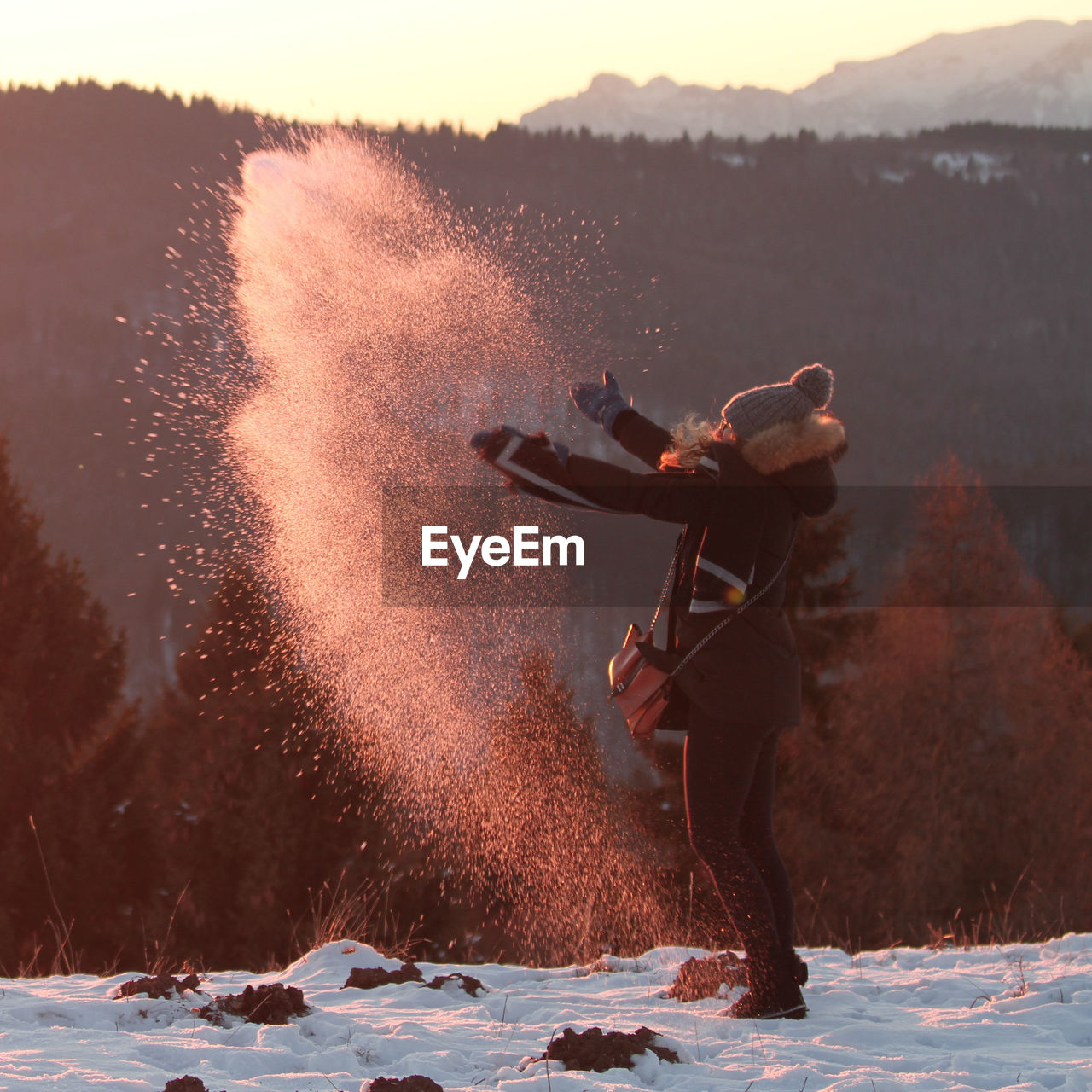 Caucasian blonde haired girl playing with snow in the mountains