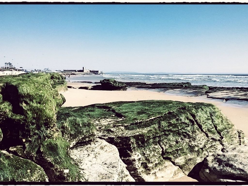 View of calm beach against clear sky