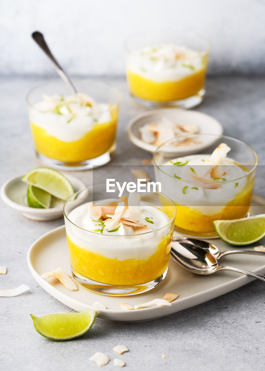 Sweet mango puree, cream cheese layered dessert decorated with roasted coconut chips and lime zest