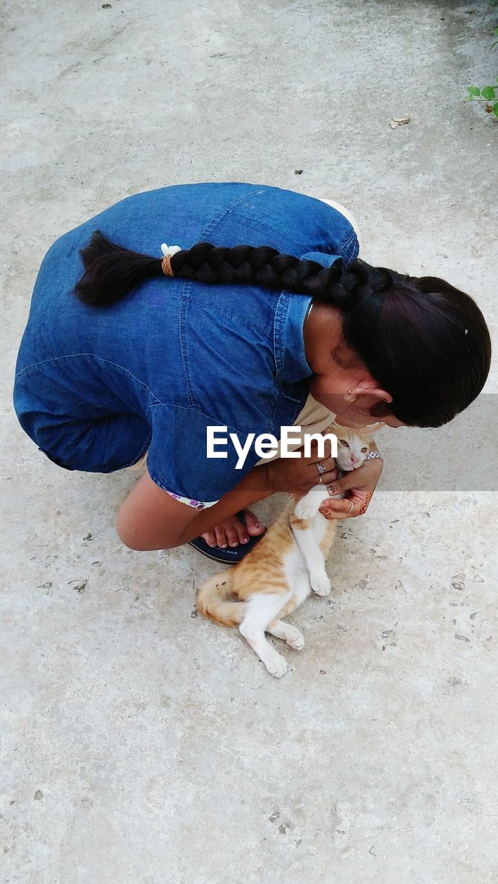 High angle view of woman embracing cat on footpath