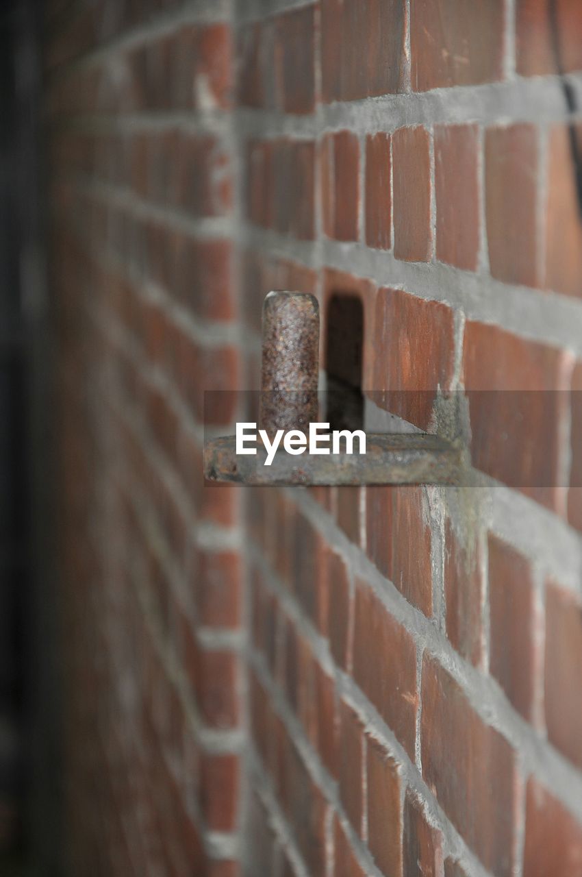 Close-up of rusty metal on red brick wall