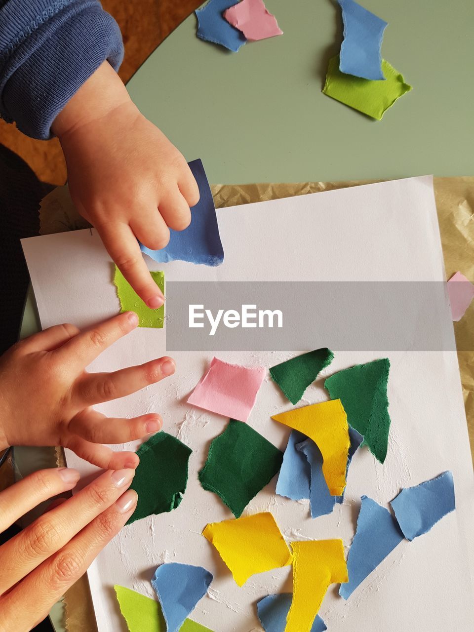 HIGH ANGLE VIEW OF HAND HOLDING MULTI COLORED PAPER WITH KNIFE